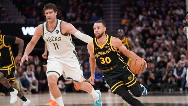 Golden State Warriors guard Stephen Curry (30) dribbles past Milwaukee Bucks center Brook Lopez (11) i
